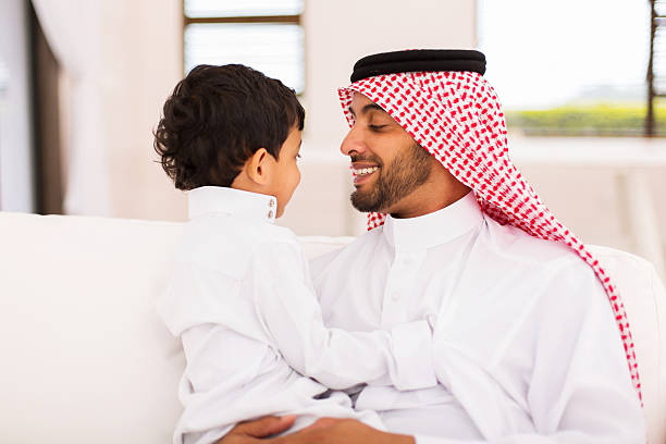 arabian father and son sitting at home portrait of happy arabian father and son sitting at home pics of a cute muslim outfits stock pictures, royalty-free photos & images
