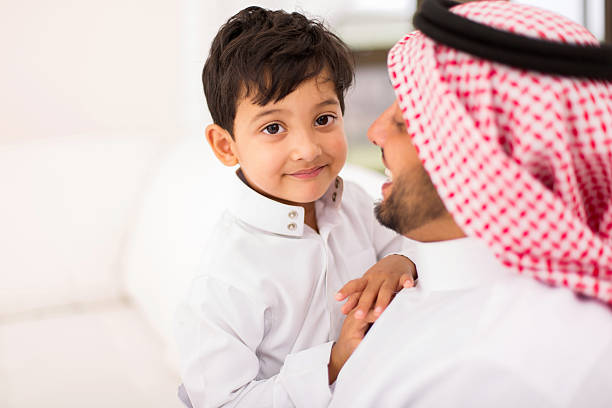 piccolo ragazzo arabo e suo padre rilassante a casa - ghoutra foto e immagini stock