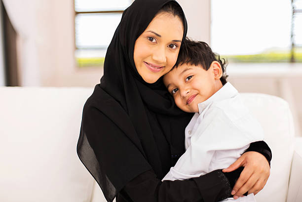 istock young muslim woman sitting on couch with her son 513387370