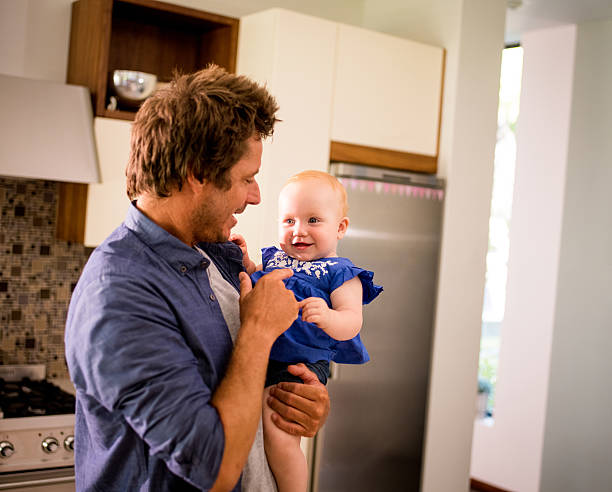 istock Modern Dad Holding and Playing with Infant Daughter in Kitchen 513387910