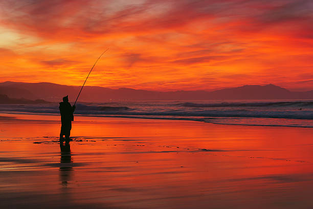 istock fisherman silhouette on beach at sunset 513388032
