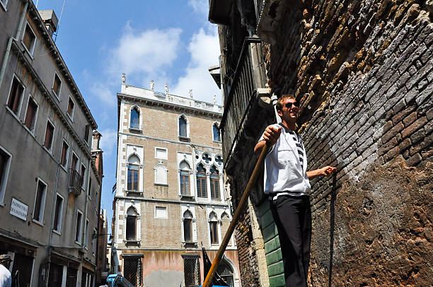 гондольер работает в венецианской гондоле в канал в венеции. - europe sunlight river sun стоковые фото и изображения