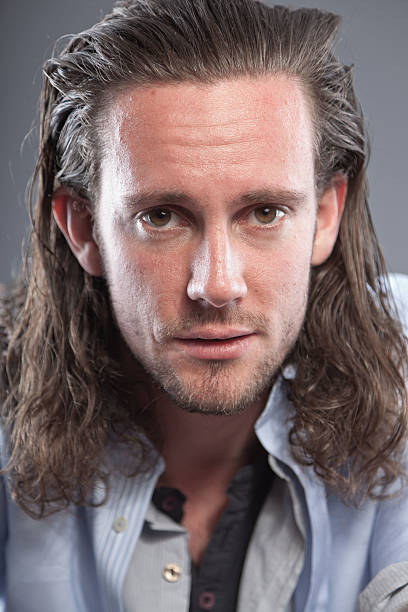 istock Man with long hair and expressive face wearing blue shirt. 513391925