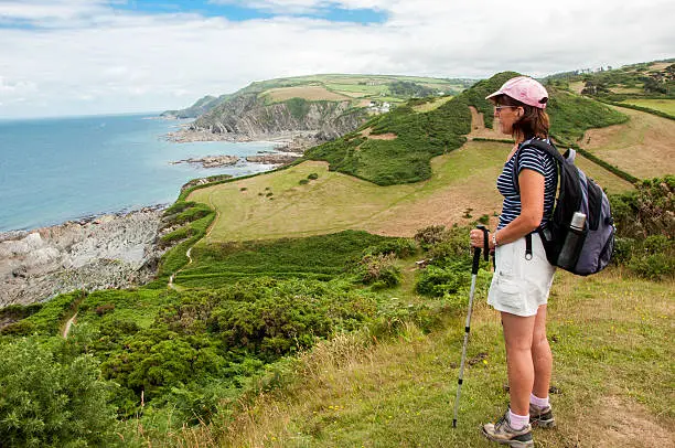 Lee Bay viewed by woman hiker, with rucksack and walking poles, on the South West Coastal Path in Devon UK. Grid reference 51.199265 -4.187370 photographed in July 2014 Copy space,horizontal photograph. CampHike2014 