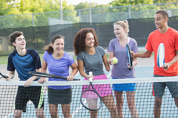 Teenagers playing tennis Multi-ethnic teenagers playing tennis.  Girl in middle (17 years, mixed race) is a physically challenged amputee. tennis teenager sport playing stock pictures, royalty-free photos & images