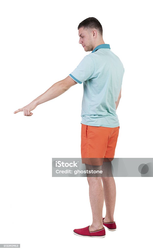 Back view of  pointing young men in  t-shirt and shorts. Back view of  pointing young men in  t-shirt and shorts. Young guy  gesture. Rear view people collection.  backside view of person.  Isolated over white background. Adult Stock Photo