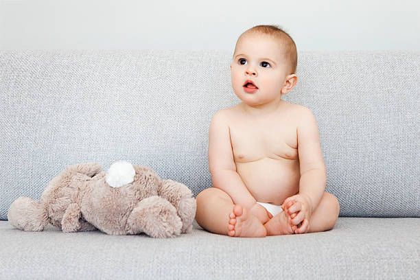 A small beautiful baby is dressed in a diaper and lies on the bed.