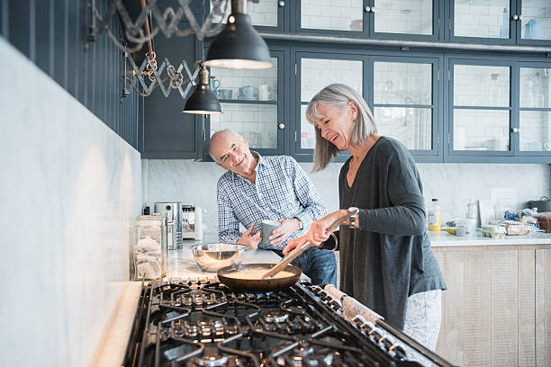 senior mujer hacer la cena hablar con su marido - cooking men caucasian togetherness fotografías e imágenes de stock