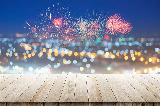 Wood floor with defocused abstract city night lights with fireworks background viewpoint on the mountain