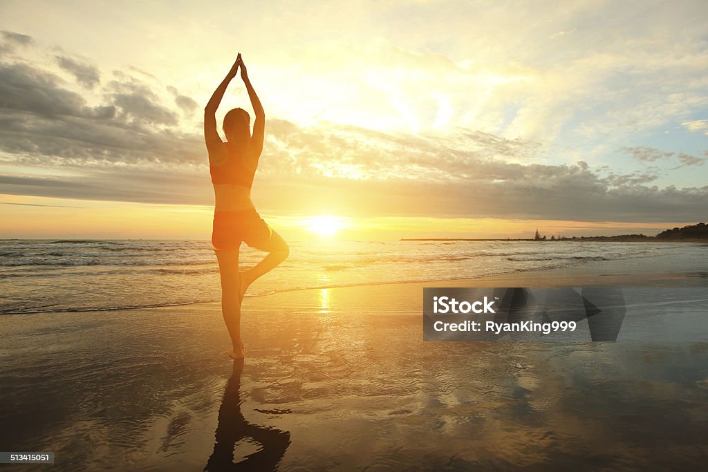 Yoga Young woman silhouette practicing yoga on the sea beach at sunset Adult Stock Photo