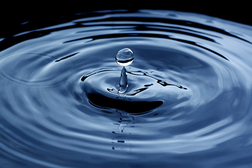 Splashing blue water drop close up background