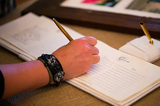 Person signing the guestbook at a wedding ceremony and reception.