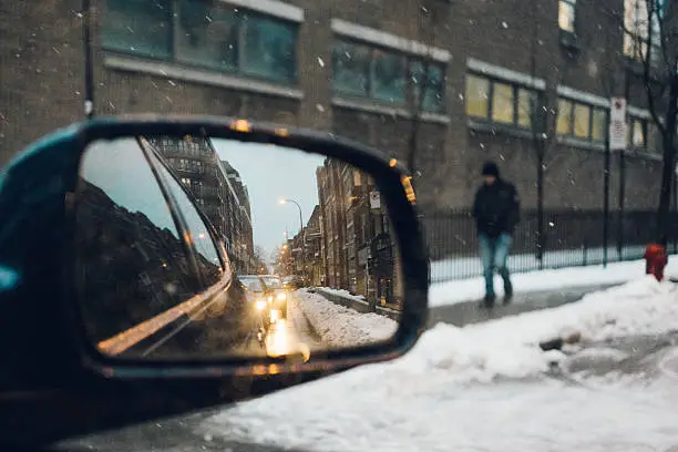 Urban traffic view from a side mirror in a cold winter day of Montreal