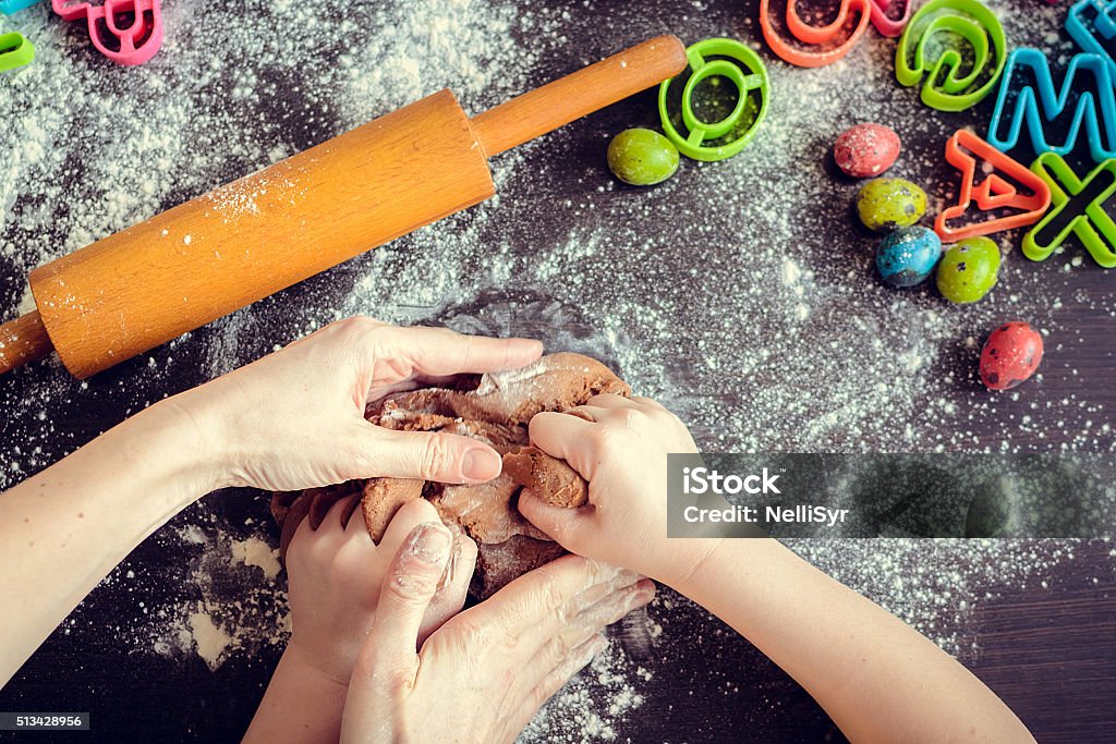 Mother teaching daughter how to make dough Hands of mother and daughter kneading dough together in the kitchen. Mother teaching daughter how to bake cookies for holidays. Easter baking preparation. Easter food concept. Top view. Child Stock Photo
