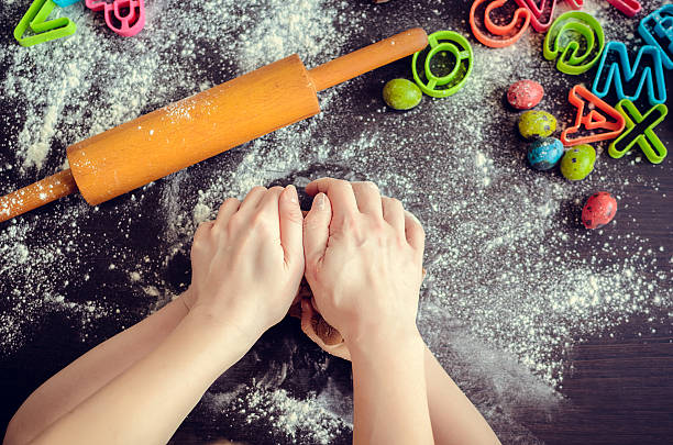 istock Mother teaching daughter how to make dough 513428970