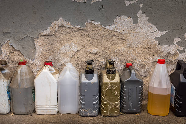 group of dirty plastic containers in front of a wall. plastic containers, oil can, grunge bottles and tanks flammable photos stock pictures, royalty-free photos & images