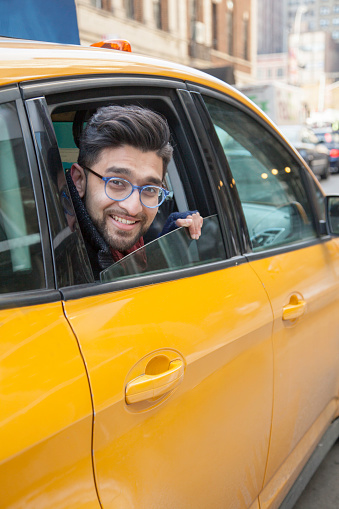 New York - March 16, 2015: Yellow taxi cabs and people rushing on busy streets of downtown Manhattan. Taxicabs with their distinctive yellow paint are a widely recognized icon of New York City.