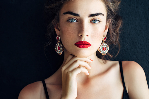 Studio shot of young beautiful woman with earings haute couture. Professional make-up and hairstyle