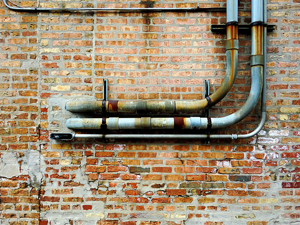 istock Industrial rusty pipes against urban old brick wall texture 513430880