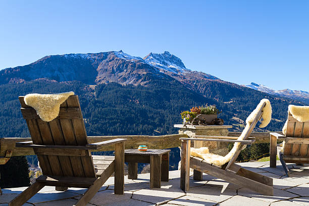 Wooden easy chairs at a mountain lodge terrace, Klosters Switzer Wooden easy chairs at a mountain lodge terrace with panoramic view of beautiful alpine landscape in autumn at the Klosters - Davos region, Switzerland. chalet stock pictures, royalty-free photos & images
