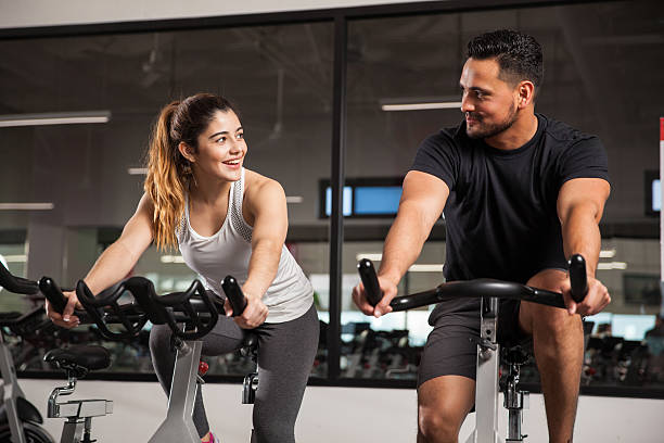 симпатичный молодая пара в тренажерный зал флирт - exercising sport gym spinning стоковые фото и изображения