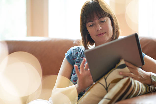 Mature woman browsing the internet on a digital tablet stock photo