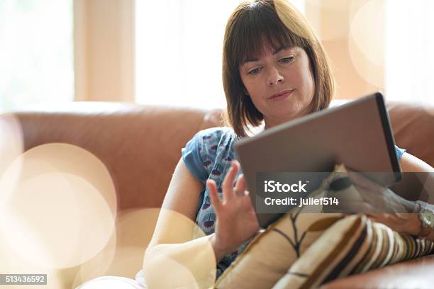 Mature Woman Browsing The Internet On A Digital Tablet Stock Photo - Download Image Now