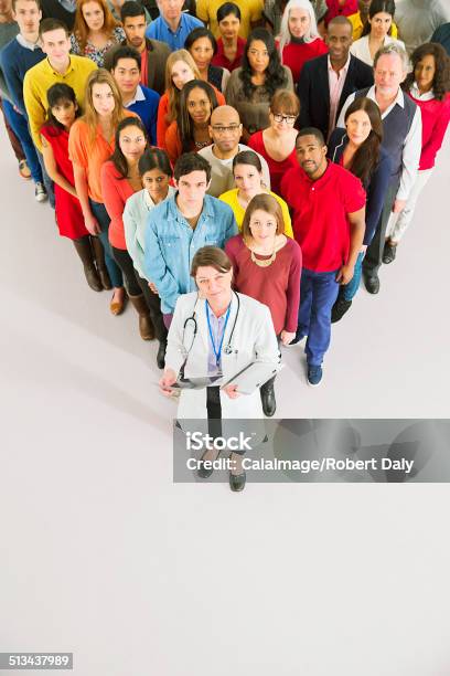 Doctor Standing In Front Of Diverse Crowd Stock Photo - Download Image Now - Patient, People, Healthcare And Medicine