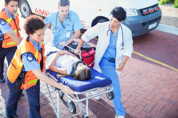 Photo of Doctor, nurse and paramedics wheeling patient on stretcher