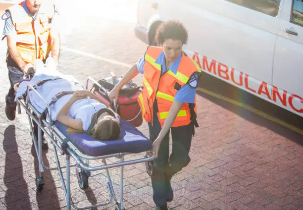 Photo of Paramedics wheeling patient in hospital parking lot