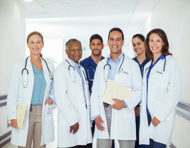 врачи и медсестры улыбаются в больничном коридоре - doctor стоковые фото и изображения