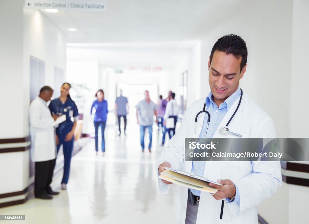 Doctor reading medical chart in hospital hallway  Doctor Stock Photo