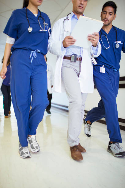 medico e infermieri che leggono la cartella clinica nel corridoio dell'ospedale - serious nurse doctor ethnic foto e immagini stock