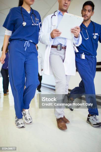 Doctor And Nurses Reading Medical Chart In Hospital Hallway Stock Photo - Download Image Now