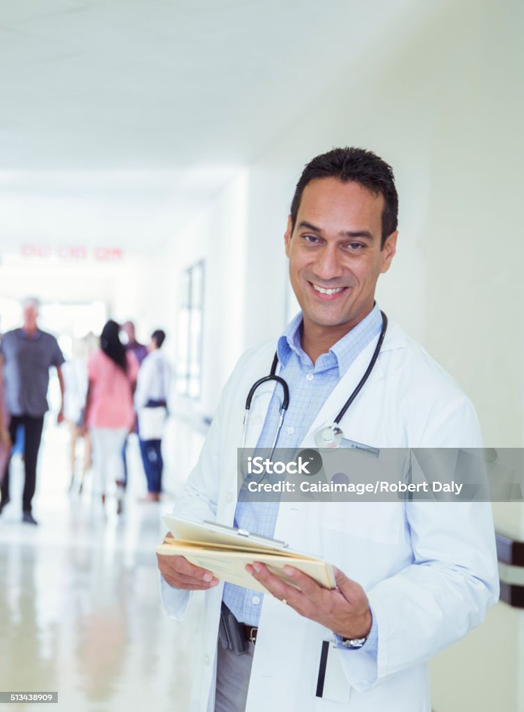 Doctor reading medical chart in hospital hallway  One Person Stock Photo