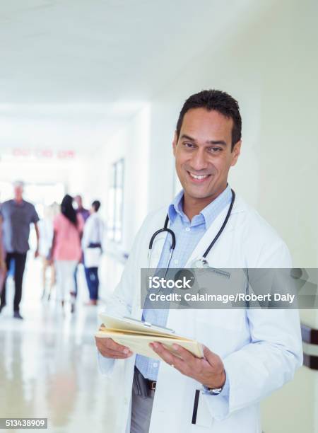 Doctor Reading Medical Chart In Hospital Hallway Stock Photo - Download Image Now - One Person, People, Stethoscope