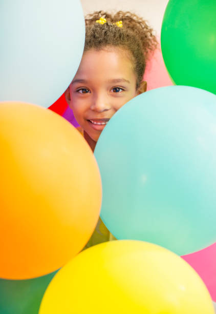 Asian little Chinese girl flying with colorful balloons against the background of sunset