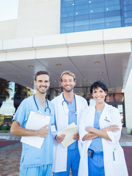 médecins et infirmière souriant à l’extérieur de l’hôpital - healthcare and medicine smiling group of people lab coat photos et images de collection