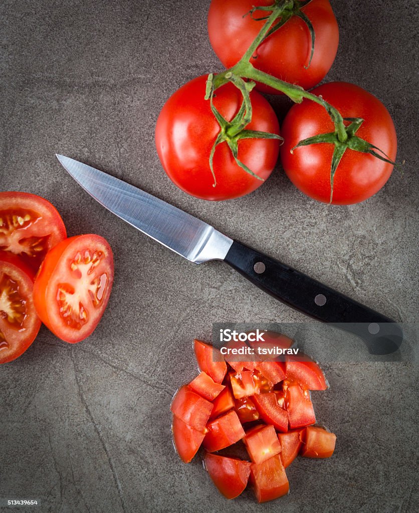 Truss tomatoes top view Truss tomatoes and kitchen knife arranged on textured stone surface. Top view. Tomato Stock Photo