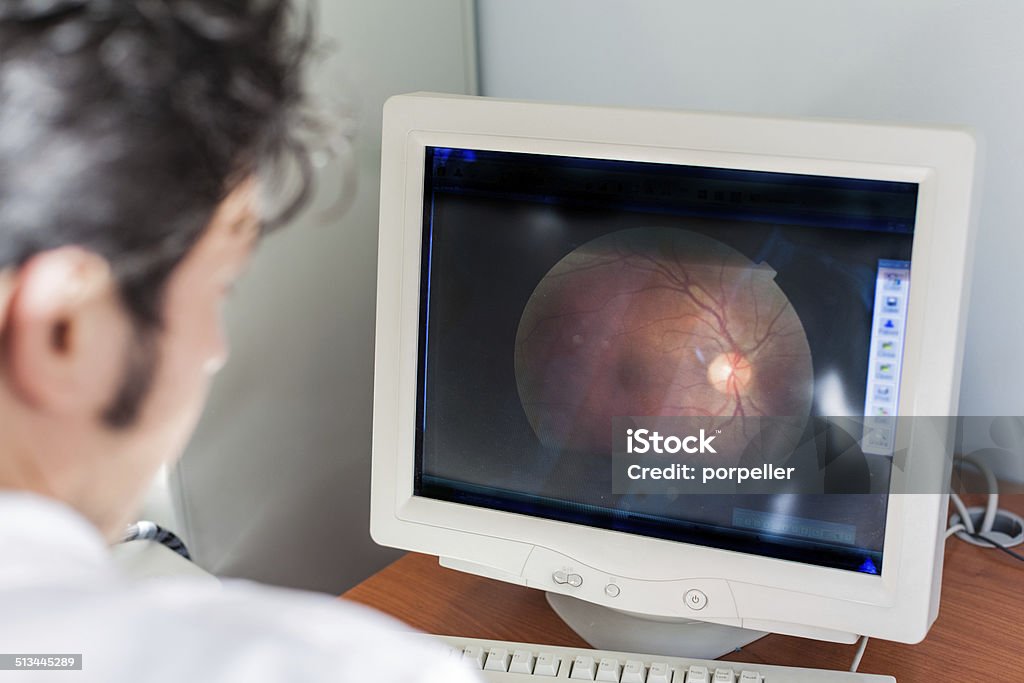 Retina a young ophthalmologist looking at a retina scan in a computer monitor Retina Stock Photo