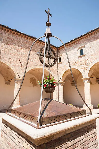 Water well in center of Italian courtyard surrounded by arched portico.