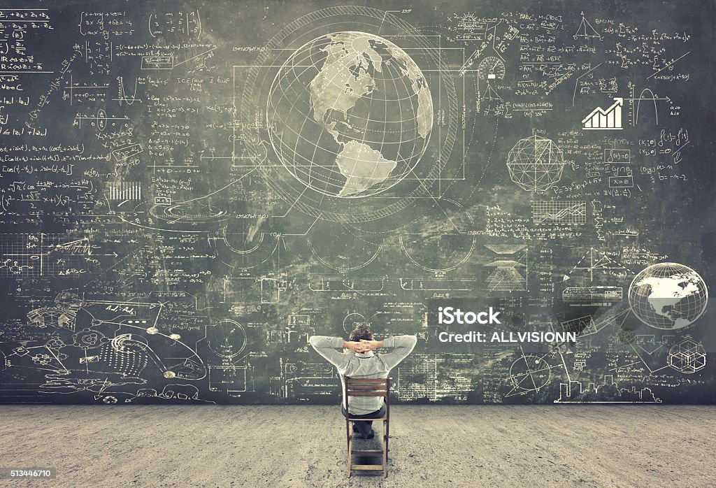 Businessman watching formulas Businessman sitting on a chair and studying math formulas on blackboard Mathematical Symbol Stock Photo