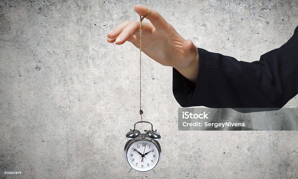 Time concept Close up of businessman holding clock on rope Abstract Stock Photo