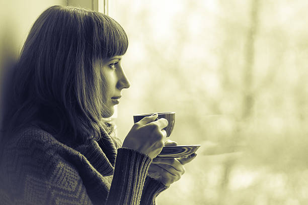 istock Beautiful girl drinking coffee or tea near window. Toned Image 513450489