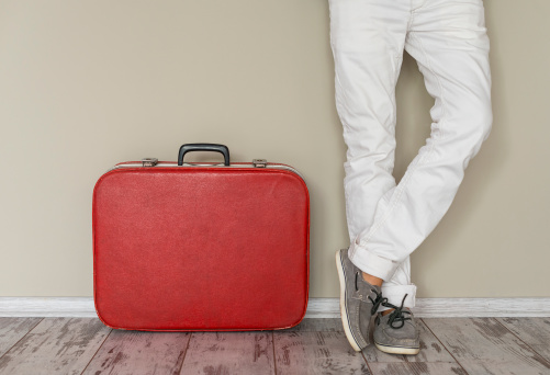 Man stands beside suitcase, home interior