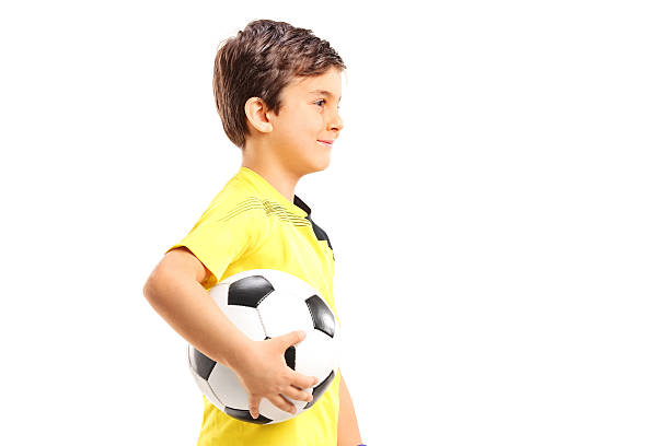 istock Young boy walking and holding a football isolated on white 513469855