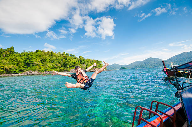 istock Man jumping off the boat into the ocean 513471184
