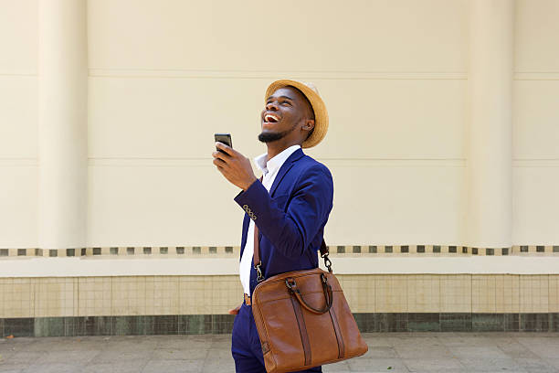 африканский бизнесмен ходьба с мобильный телефон и сумка - men african descent looking up smart casual стоковые фото и изображения