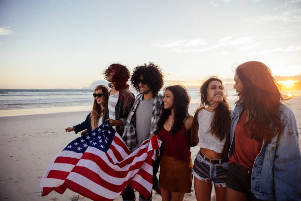 istock Hipster friends holding an American flag during a beach walk 513473618