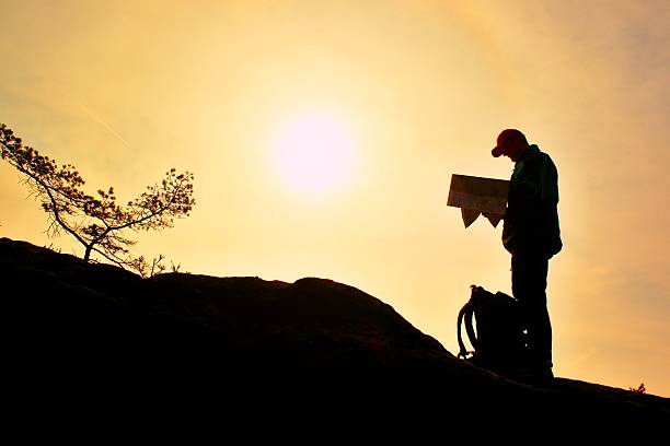 istock Silhouette of young man looking at a map while hiking 513475262